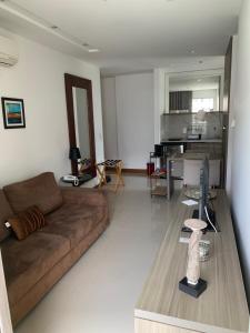 ein Wohnzimmer mit einem braunen Sofa und einem Tisch in der Unterkunft Flat moderno e sofisticado in Rio de Janeiro