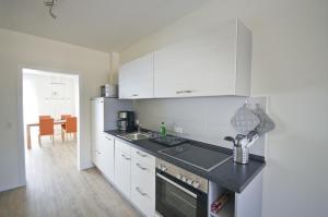 una cucina con armadi bianchi e piano di lavoro nero di Appartements Am Kurpark a Bad Windsheim