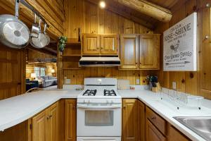 Il comprend une cuisine équipée d'une cuisinière blanche et de placards en bois. dans l'établissement Hartland Cabin, à Hartland