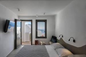 a bedroom with a large bed and a tv at Kasimatis by La Perla - Adults Only in Imerovigli