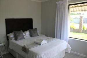 a bedroom with a white bed with a window at Framesby Guesthouse in Port Elizabeth
