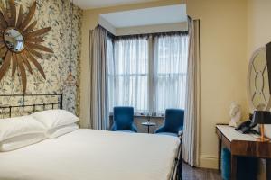 a hotel room with a bed and two blue chairs at Crown Hotel in Stamford