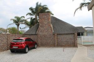 een rode auto geparkeerd voor een stenen muur bij Framesby Guesthouse in Port Elizabeth