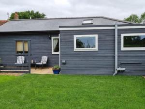 una casa gris con dos sillas en un patio en The Snuggery Broadclyst en Exeter