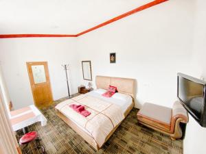 a bedroom with a bed and a flat screen tv at Berghaus Bungalow in Ella