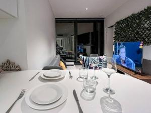 een witte tafel met borden en wijnglazen erop bij Amazing 2 Bedroom in CBD! in Brisbane