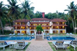 een resort met een zwembad en palmbomen bij The Travancore Heritage Beach Resort in Kovalam