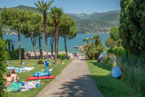 people laying on the grass at a beach at Albatross Mobile Homes on Camping Eden in San Felice del Benaco