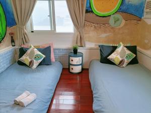 two beds in a small room with windows at Rabbit芮比特 in Kenting