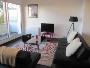 a living room with a couch and a television at Villa Régina in Trouville-sur-Mer