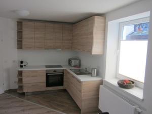 una pequeña cocina con armarios de madera y una ventana en Alpeneer, en Lackenhof