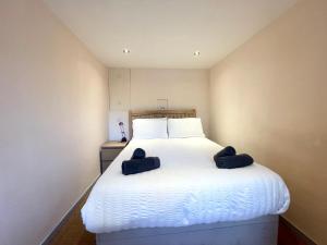 a bedroom with a white bed with two blue slippers on it at Richmond House (9A) by Staytor Accommodation in Exeter