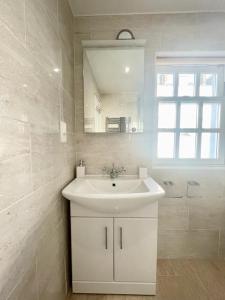 Baño blanco con lavabo y espejo en Richmond House (9A) by Staytor Accommodation en Exeter