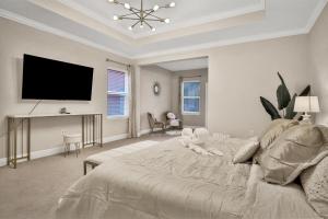 a white bedroom with a bed and a flat screen tv at Newport Retreat in Tampa