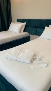 dwa łóżka z białymi ręcznikami i kubkiem na nich w obiekcie Jardin w mieście Aktobe