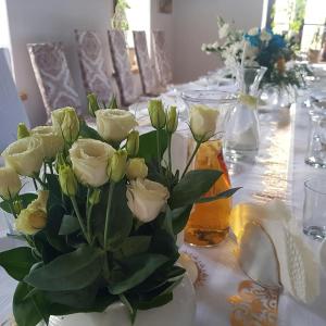 a table with a vase of white roses on it at Pokoje Gościnne Art- Dworek in Kudowa-Zdrój