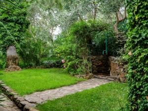 d'un jardin avec un mur en pierre et de l'herbe verte. dans l'établissement Residence L'Ulivo, à Budoni