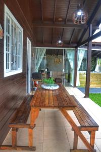 una mesa de picnic de madera en el porche de una casa en Recanto Aloha Kaii, en Palhoça