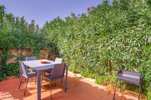 a table and chairs on a patio with a hedge at Vila Bela Nova Acácias 22 in Luz