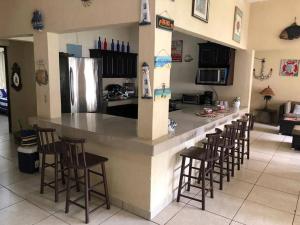 a kitchen with a large counter with stools in a room at Casa Los Cocos Monterrico in Monterrico