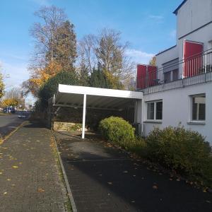 a building with a white canopy next to a street at Haus Hillebrand in Bad Honnef am Rhein