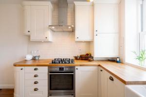 a kitchen with white cabinets and a stove top oven at Pass the Keys Stylish Apartment in the heart of Clerkenwell in London