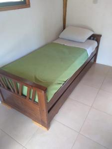 a wooden bed with a green mattress on a floor at La Maruca in El Hoyo