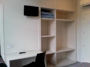 a room with a desk with a tv and shelves at Estació Del Nord in Vic