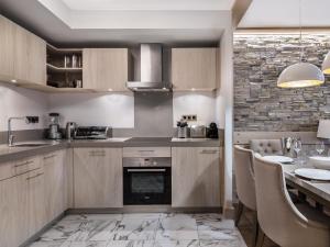 a kitchen with wooden cabinets and a table with chairs at Appartement moderne à Courchevel Village, près des commerces et pistes, parking et salle de fitness inclus - FR-1-562-38 in Courchevel +2 photos