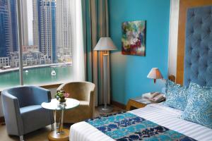 Habitación de hotel con cama, silla y ventana en Marina Byblos Hotel, en Dubái