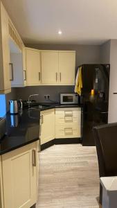 a kitchen with white cabinets and a black refrigerator at Stylish 1st Floor flat Free Parking 2mins from Junction 48A1m in Boroughbridge