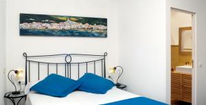 a bedroom with a bed with blue pillows and a painting on the wall at Casa Rural El Pati de l´Albera in Sant Climent Sescebes