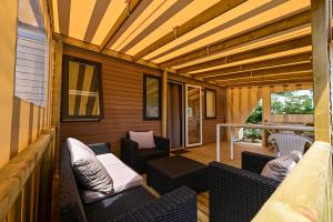 アンボンにあるCamping Paradis d'Arvorの籐椅子と木製天井のスクリーンポーチ