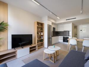 ein Wohnzimmer mit Fernseher und Tisch und Stühlen in der Unterkunft VV Arenas de Guanarteme "by henrypole home" in Las Palmas de Gran Canaria