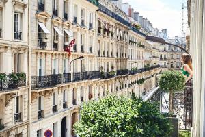 une femme debout sur un balcon devant un bâtiment dans l'établissement Hotel Cervantes by Happyculture, à Paris