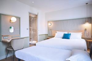 a hotel room with two beds and a television at Hotel Cervantes by Happyculture in Paris