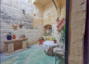 a room with a table and chairs in a building at Peaceful Farmhouse stay with cozy Yard in Għarb