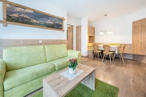 - un salon avec un canapé vert et une table dans l'établissement Haus zur Vogelweide App 1, à Dobbiaco