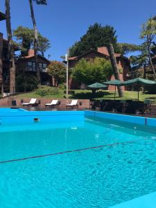 una gran piscina azul con sillas y sombrillas en Cariló Paradise Apart Hotel & Spa en Cariló