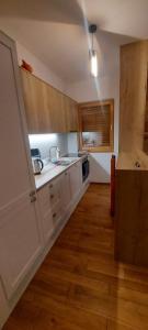 a kitchen with white cabinets and a wooden floor at Apartment Babin Do in Bjelašnica