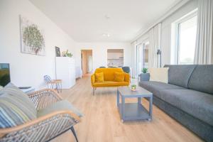 a living room with a couch and a yellow chair at Between Waves in Ostend