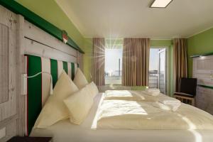 a bedroom with a large white bed with green walls at Insulaner Ferienwohnungen in Helgoland