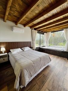 a bedroom with a large bed and a large window at Alameda dos Ipês, casa completa, para toda família in Santo Amaro da Imperatriz