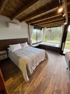 a bedroom with a bed and a large window at Alameda dos Ipês, casa completa, para toda família in Santo Amaro da Imperatriz