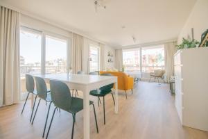 a dining room with a white table and chairs at Between Waves in Ostend