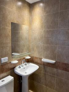 W łazience znajduje się umywalka, lustro i toaleta. w obiekcie Apart Hotel Nonquen w mieście Merlo