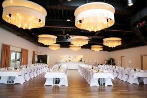 a banquet hall with white tables and chairs and chandeliers at Aircraft Hotel & Events in Neuhausen ob Eck