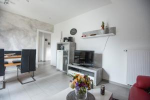 a living room with a television and a table with flowers at Wietheger´s Gästehaus Centrum in Willingen