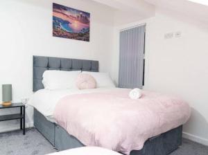 a bedroom with a large bed with pink sheets at Excel House Serviced Apartments in Leeds