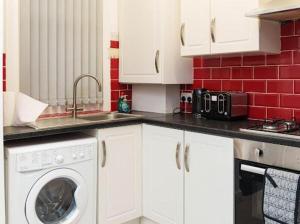 a kitchen with white cabinets and a washing machine at Excel House Serviced Apartments in Leeds